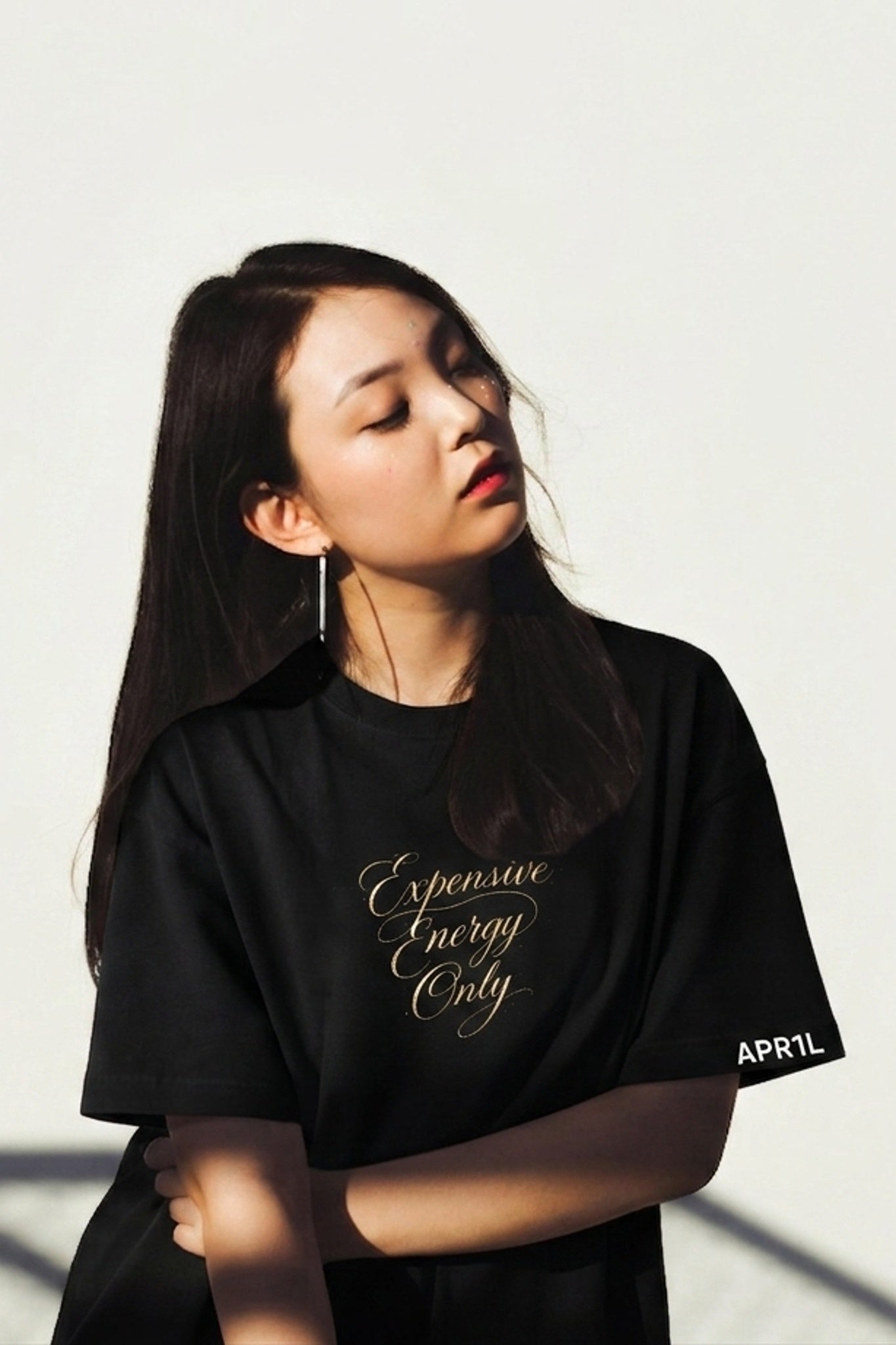 Model wearing APR1L Aura midnight black aesthetic oversized t-shirt with expensive energy only quote.